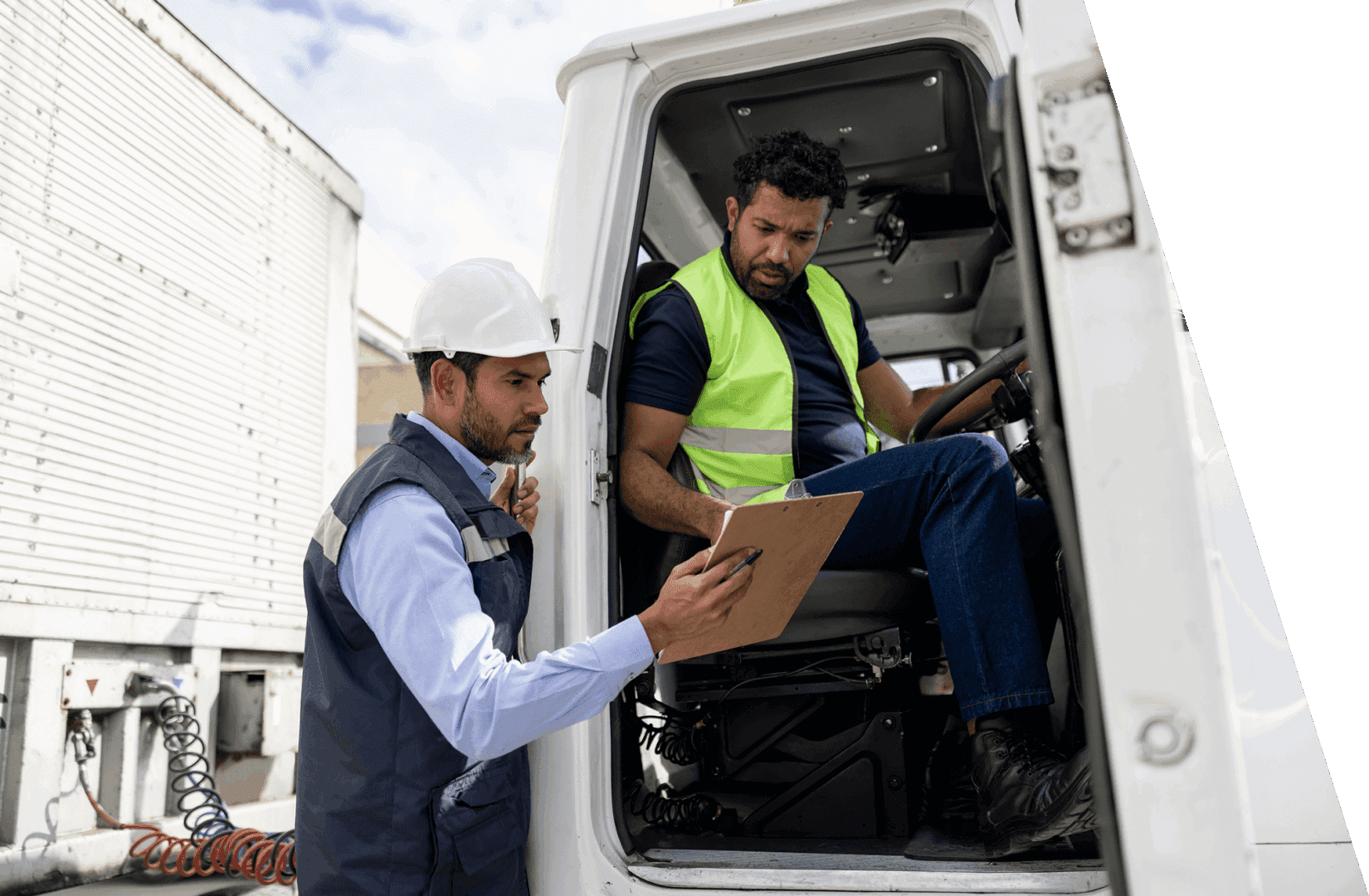 Two workers inspecting documents inside a vehicle, wearing safety gear.