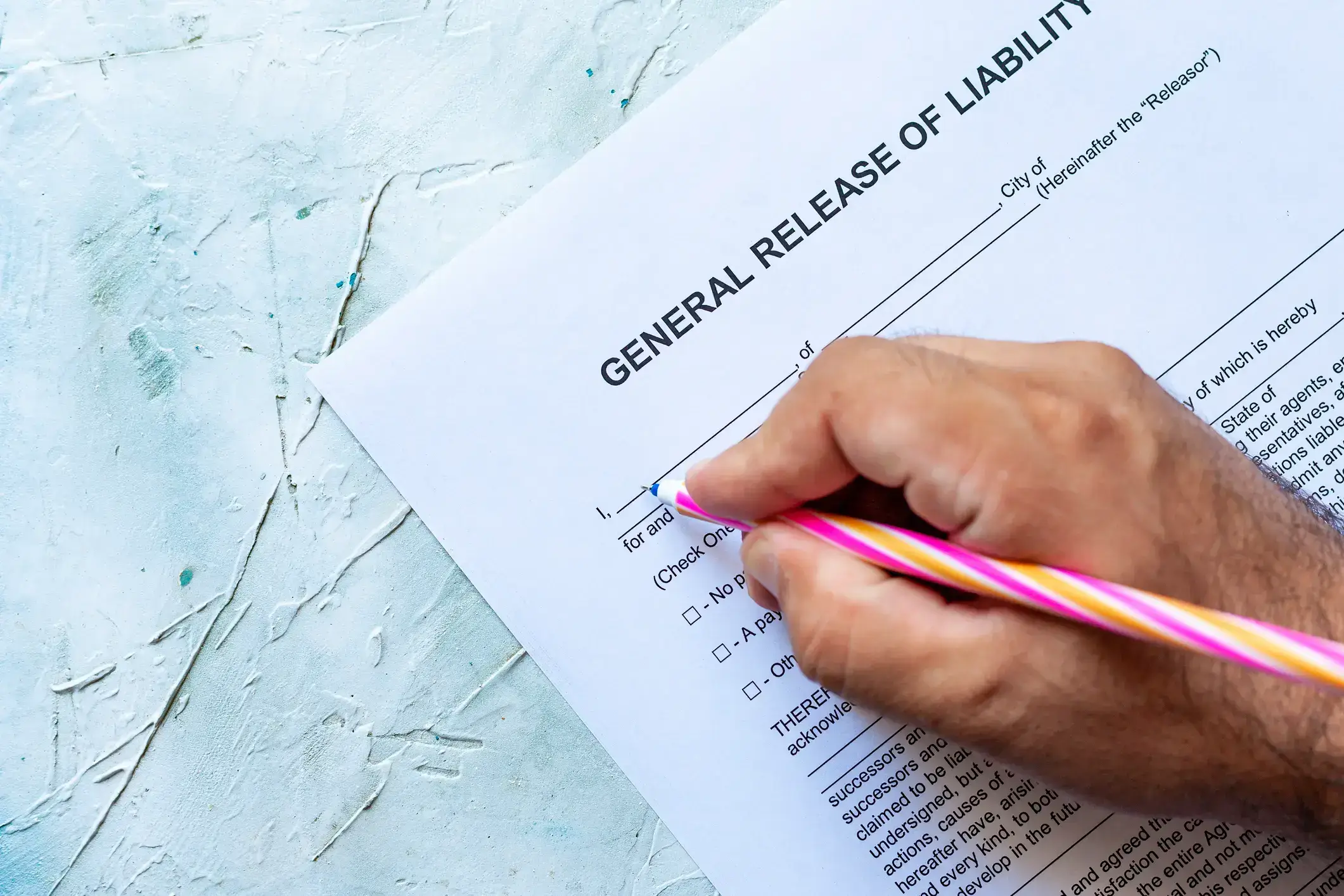 Person filling out a general release of liability form with a pink pencil.