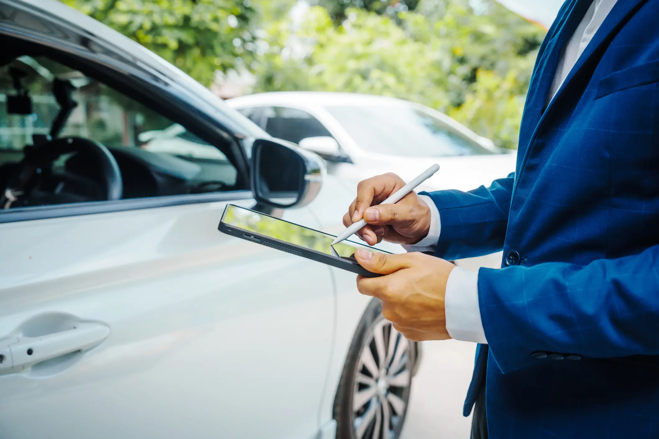 Insurance agent inspecting car damage and taking notes.